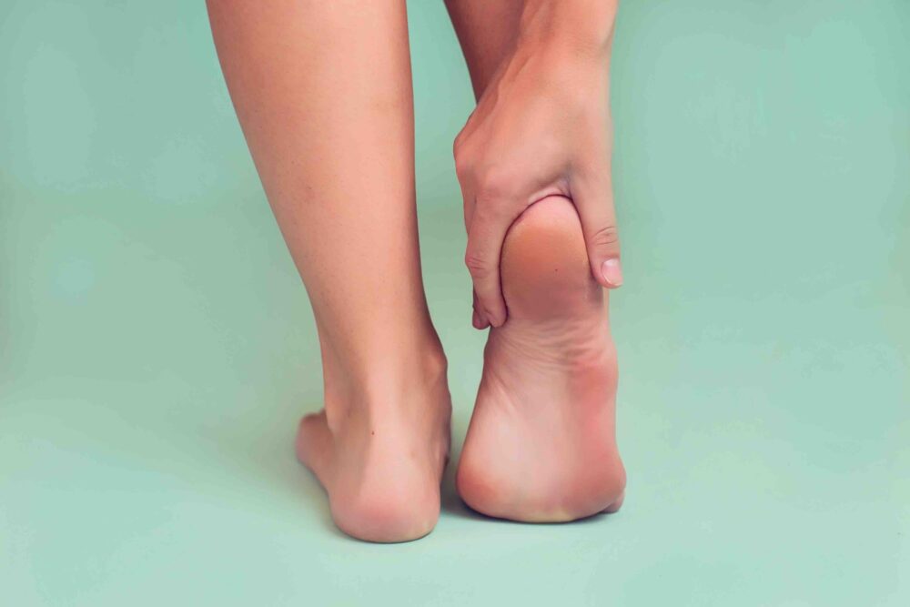 Person grasping back of foot due to heel pain