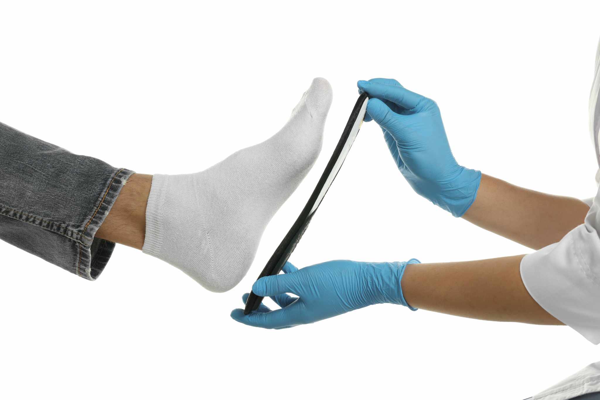 Orthopedist fitting insole to patient's foot on white background, closeup