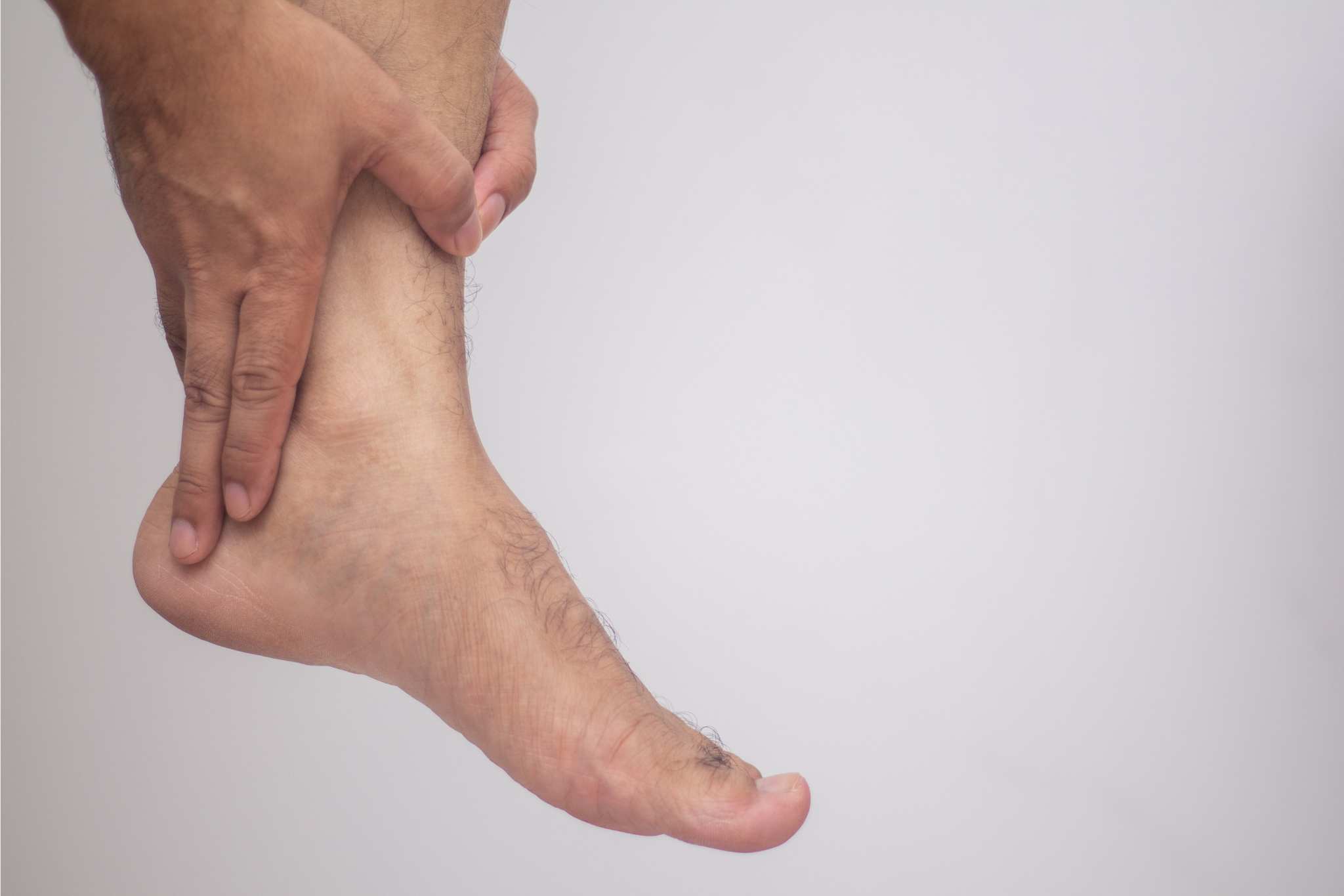 hand holding ankle (foot pain concept)