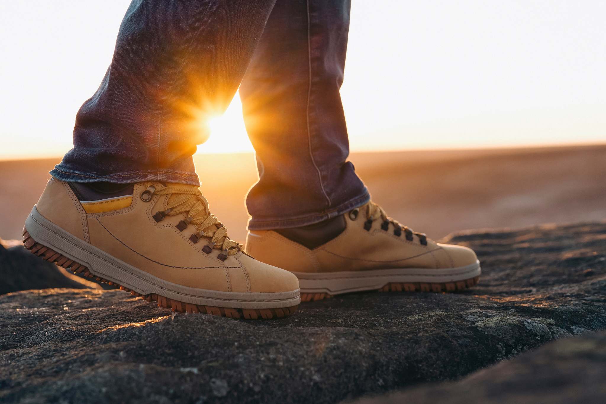 closeup of feet of man in special boots walking in the mountains reaching the destination and on the top of mountain at sunrise or sunset. Travel Lifestyle concept