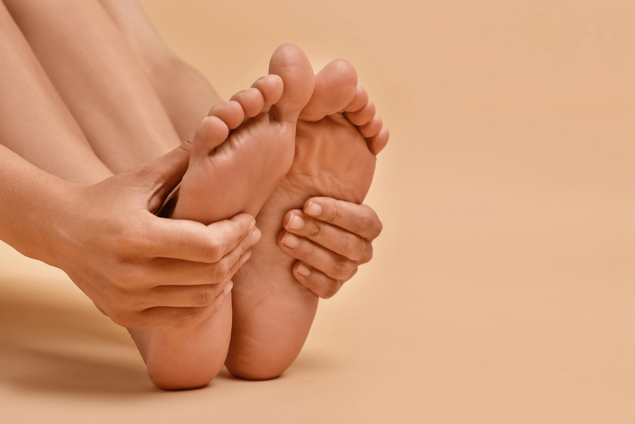 Woman touching her smooth feet on beige background