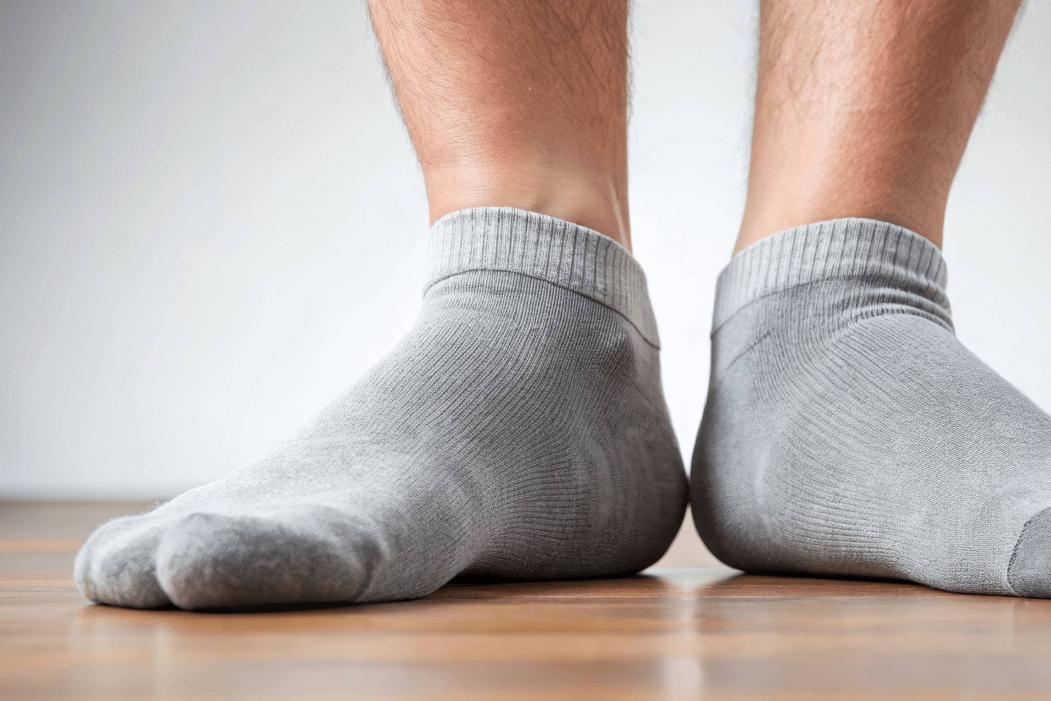Close-up of flat feet with forced-up arch in gray socks, flat feet, arch support, foot care, orthopedic
